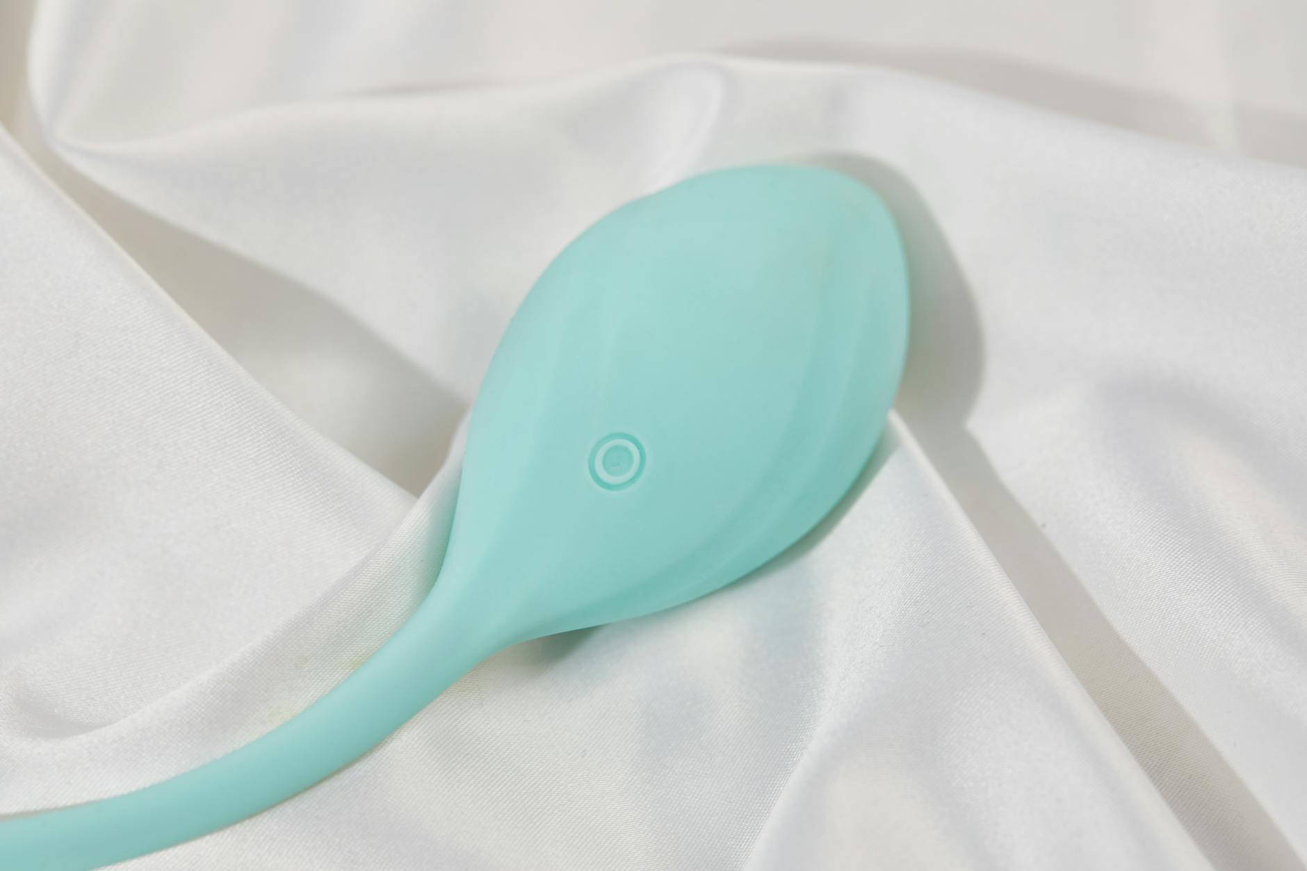 A sleek lemon-yellow clitoral vibrator resting on soft white fabric