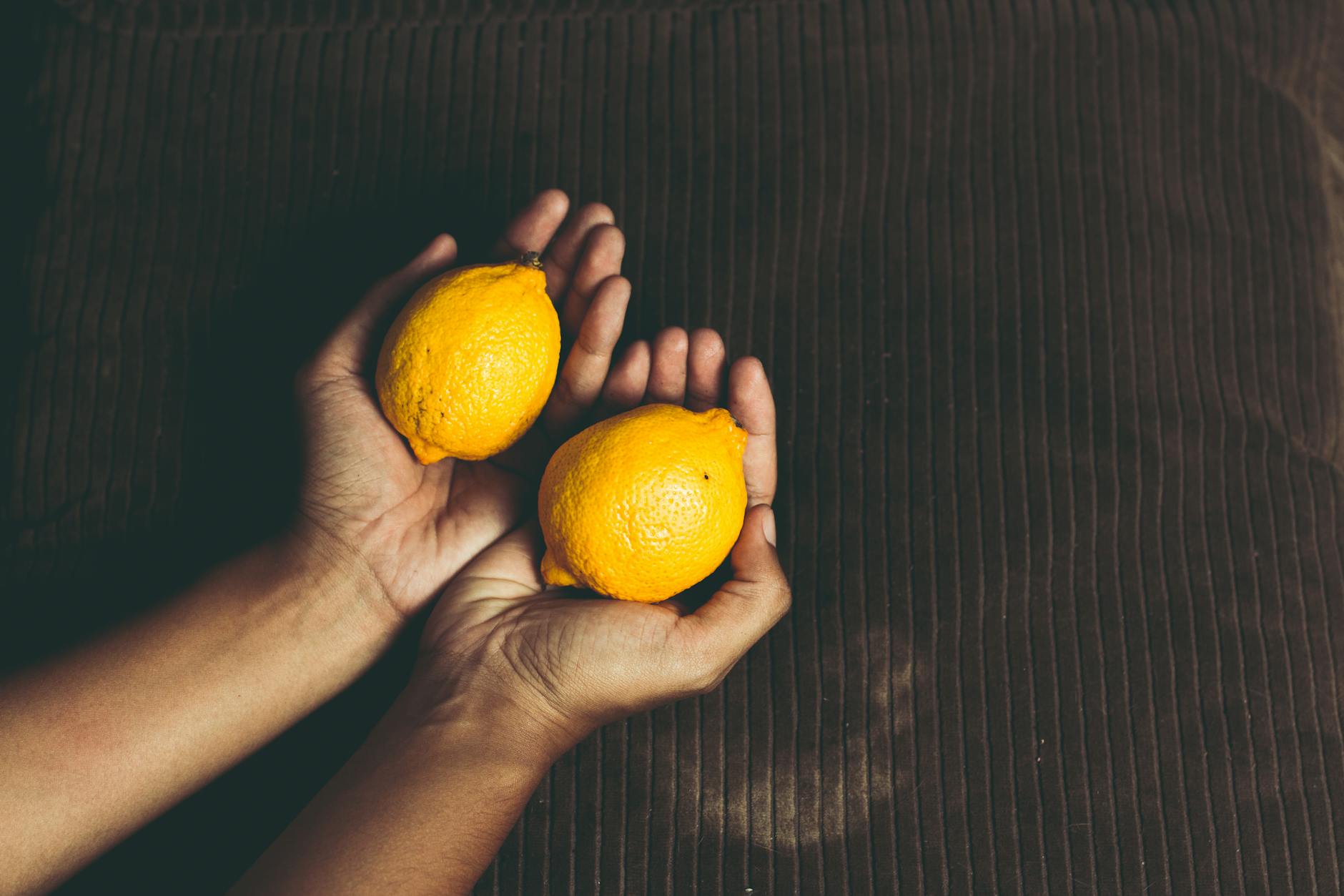 Close-up of a hand holding an orange vibrator against a minimalistic purple backdrop, showcasing modern sensuality.