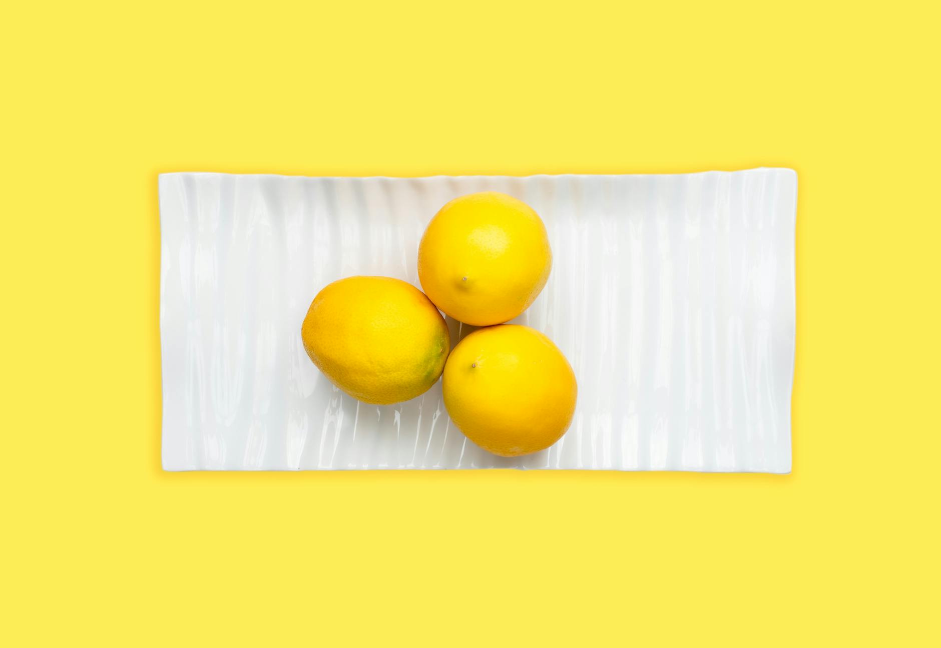 Ripe vivid lemons on a bright yellow background, symbolizing the shifting sensations of perimenopause pleasure