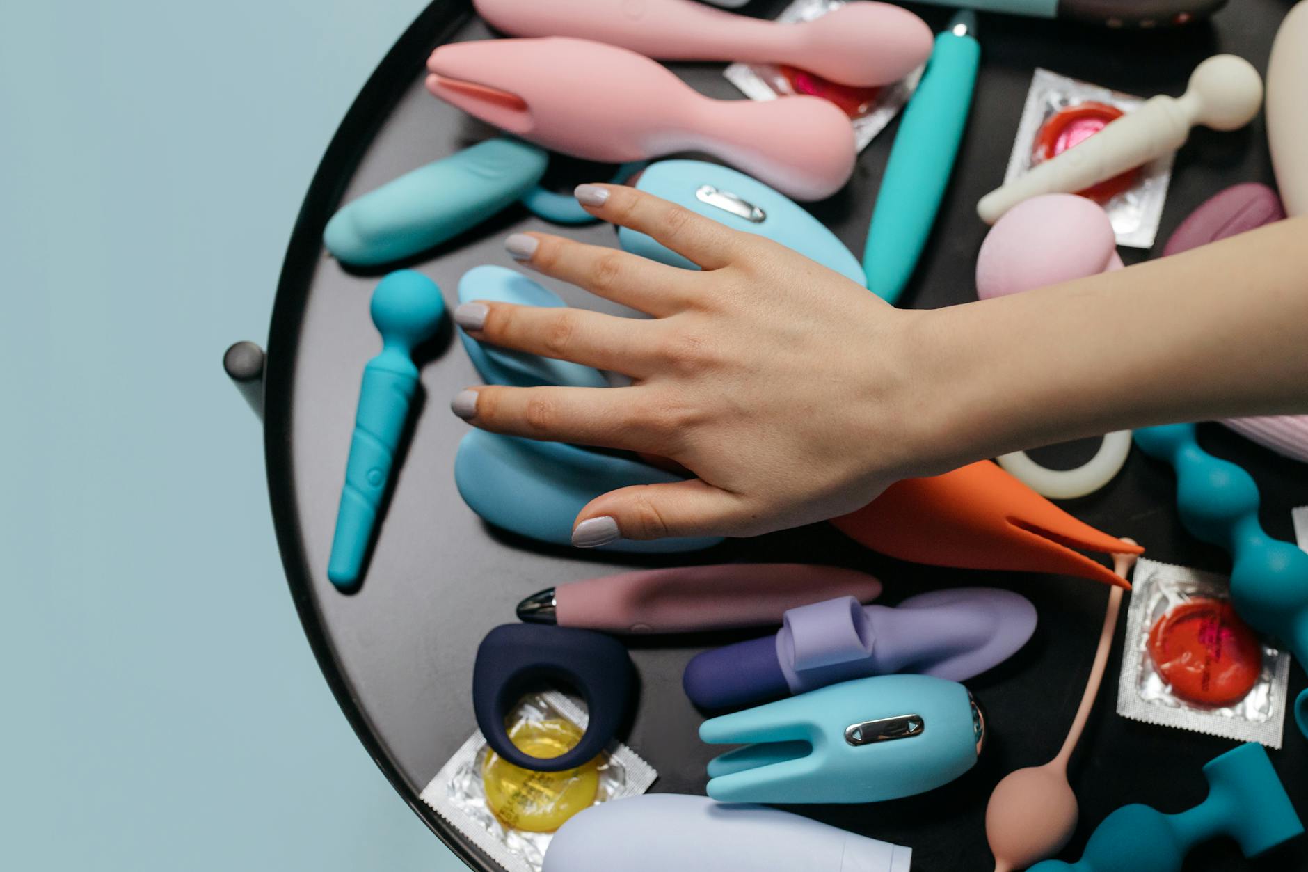 A young woman holding two colorful clitoral vibrators against a purple background
