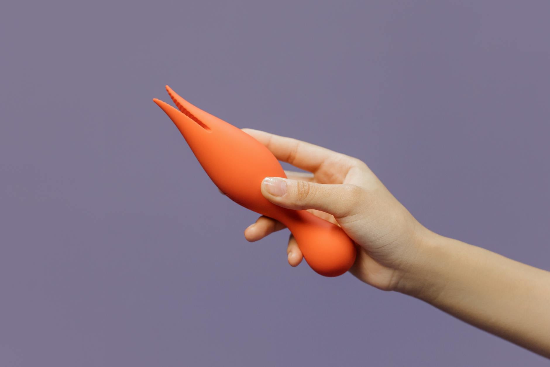 A hand holding a lemon vibrator against a minimalistic backdrop, showcasing modern sensuality.