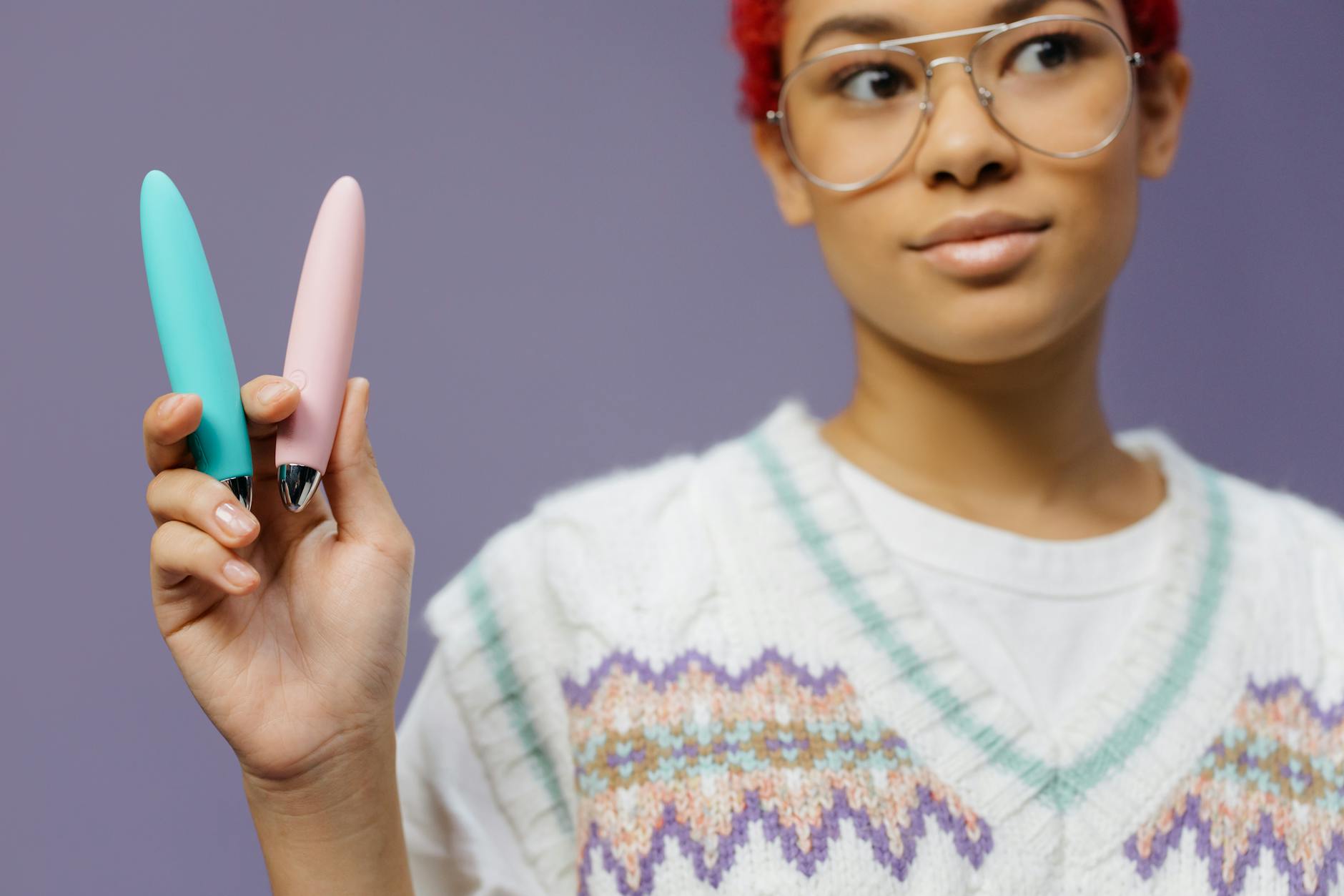 Woman holding lemon clitoral vibrators against a purple background