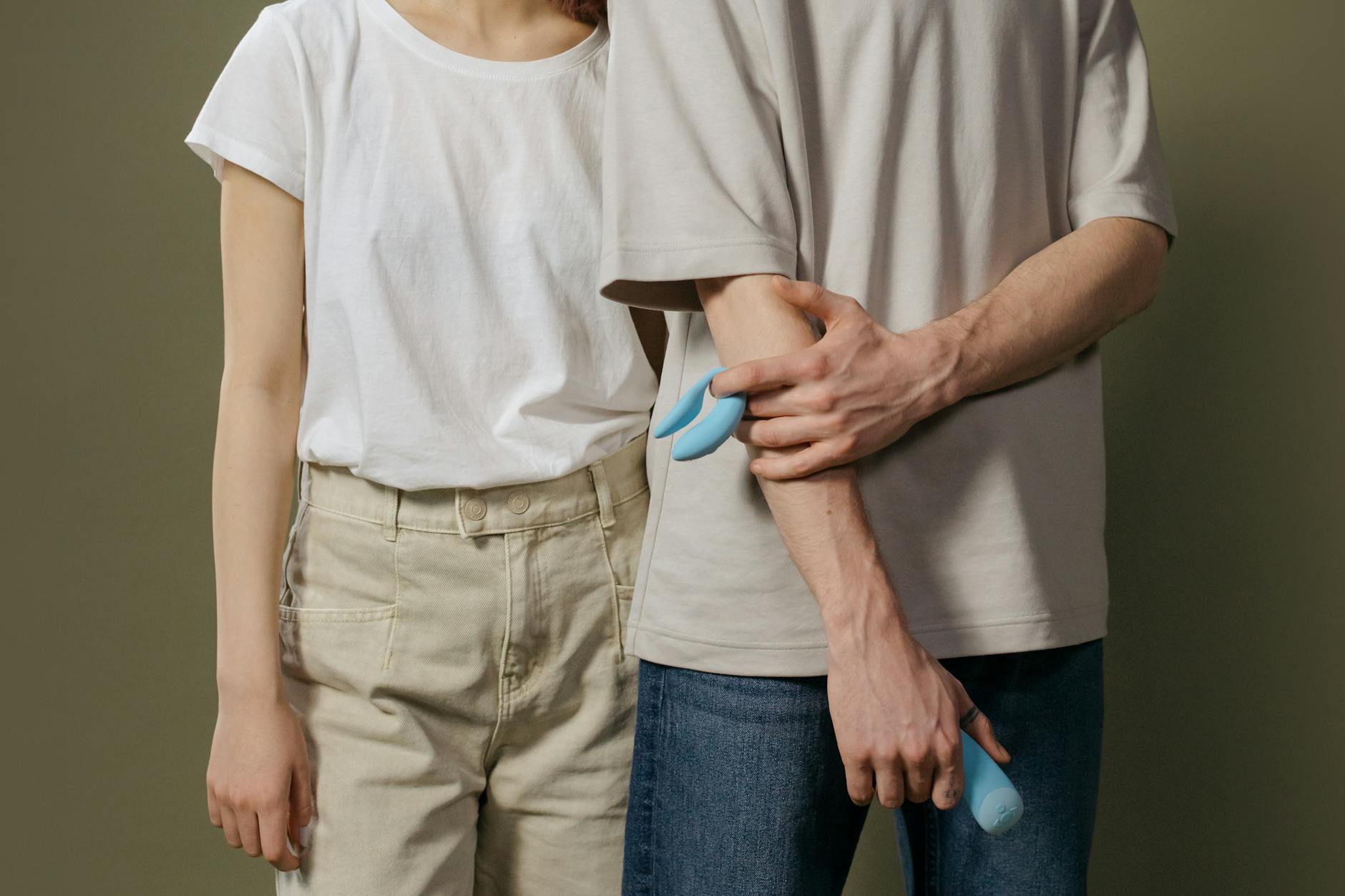 A hand holding an orange vibrator against a minimalistic purple backdrop, showcasing modern sensuality.